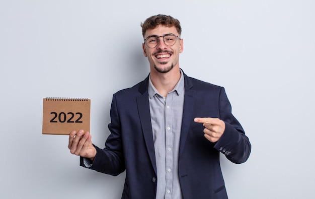 Hombre guapo joven mirando emocionado y sorprendido apuntando hacia un lado. concepto de calendario