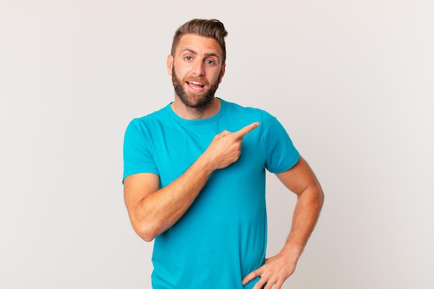 Hombre guapo joven mirando emocionado y sorprendido apuntando hacia un lado. concepto de fitness