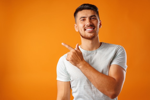 Hombre guapo joven de pie y señalando con el dedo hacia un lado