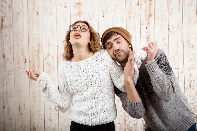 Hombre guapo joven poner nervioso a su novia sosteniendo el teléfono en madera