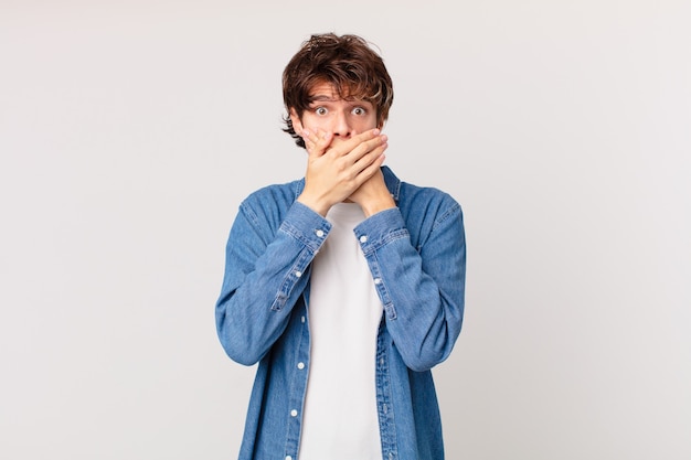 Hombre guapo joven que cubre la boca con las manos con un sorprendido