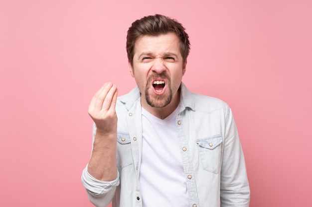 Hombre guapo joven que muestra un gesto italiano que significa qué quieres