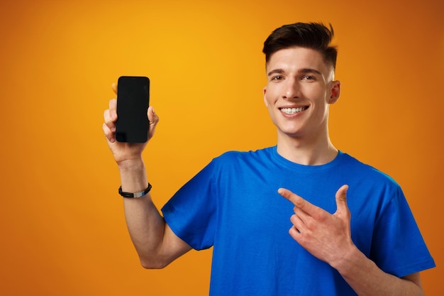 Foto hombre guapo joven que muestra la pantalla del teléfono inteligente negro