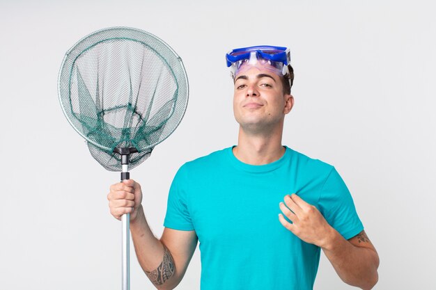 Hombre guapo joven que parece arrogante, exitoso, positivo y orgulloso con gafas y red de pesca