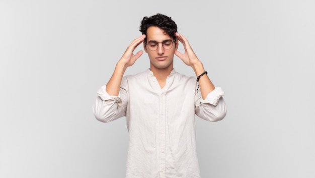 Hombre guapo joven que parece concentrado, reflexivo e inspirado, haciendo una lluvia de ideas e imaginando con las manos en la frente