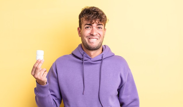 Hombre guapo joven que parece desconcertado y confundido. concepto de botella de pastillas