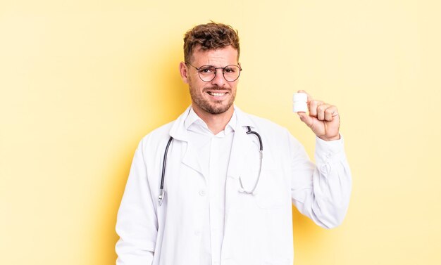 Hombre guapo joven que parece desconcertado y confundido. concepto de botella de píldoras médico