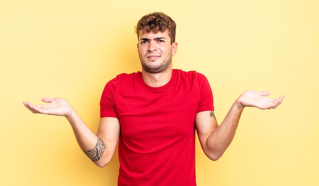 Hombre guapo joven que parece desconcertado, confundido y estresado, preguntándose entre diferentes opciones, sintiéndose inseguro