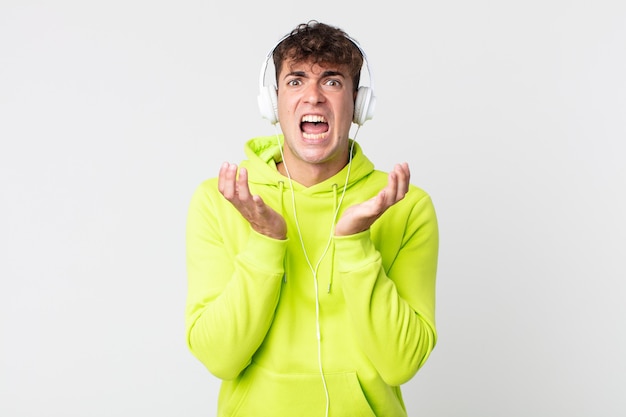 Hombre guapo joven que parece desesperado, frustrado y estresado y auriculares