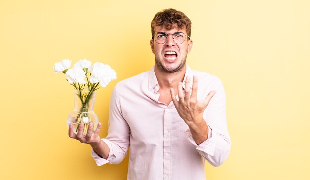 Hombre guapo joven que parece desesperado, frustrado y estresado. concepto de flores