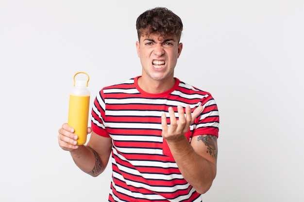 Hombre guapo joven que parece desesperado, frustrado y estresado y sosteniendo un termo de café