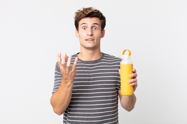 Hombre guapo joven que parece desesperado, frustrado y estresado y sosteniendo un termo de café