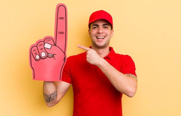 Hombre guapo joven que parece emocionado y sorprendido señalando el concepto de mano número uno del lado