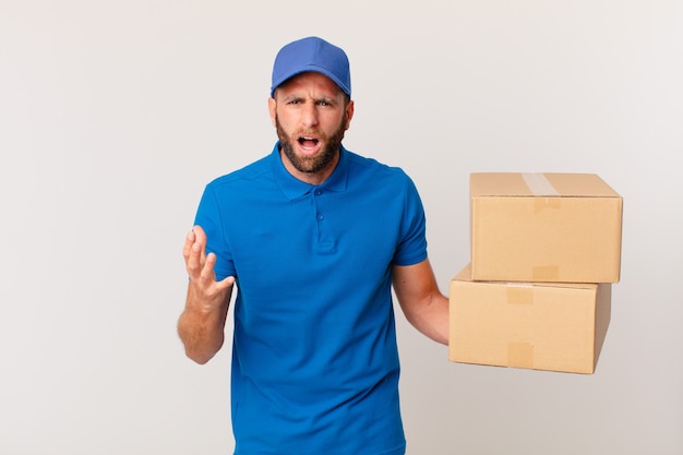 Hombre guapo joven que parece enojado, molesto y frustrado. concepto de entrega de paquetes