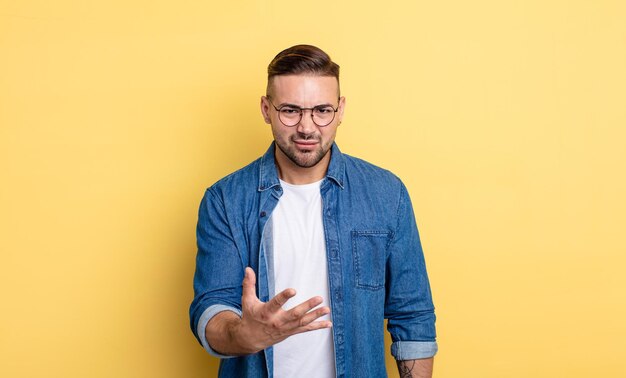 Hombre guapo joven que parece enojado, molesto y frustrado gritando wtf o qué te pasa