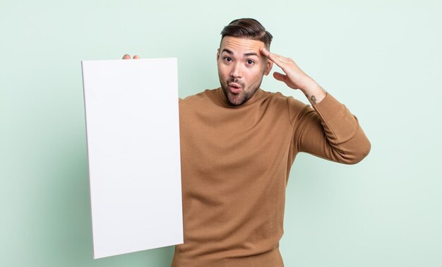 Hombre guapo joven que parece feliz, asombrado y sorprendido. concepto de lienzo vacío