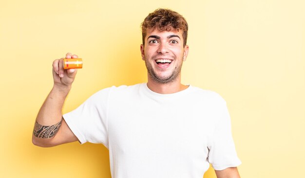 Hombre guapo joven que parece feliz y gratamente sorprendido con una batería