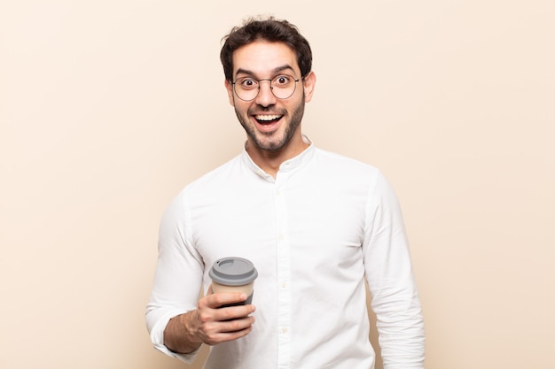 Hombre guapo joven que parece feliz y gratamente sorprendido, emocionado con una expresión fascinada y conmocionada