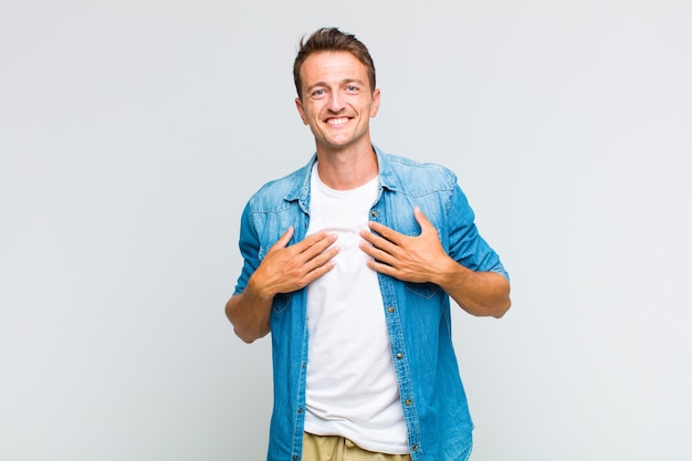 Hombre guapo joven que parece feliz, sorprendido, orgulloso y emocionado, apuntando a sí mismo