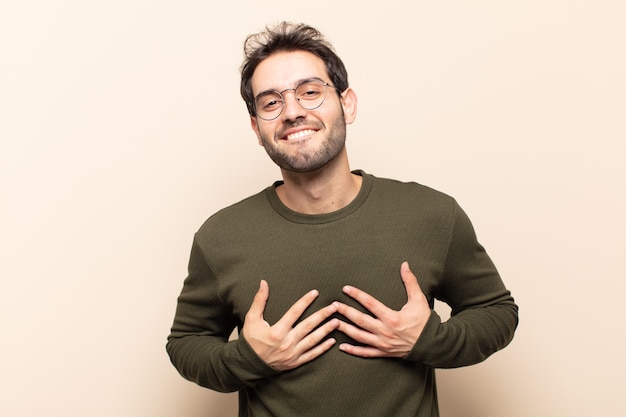 Hombre guapo joven que parece feliz, sorprendido, orgulloso y emocionado, apuntando a sí mismo