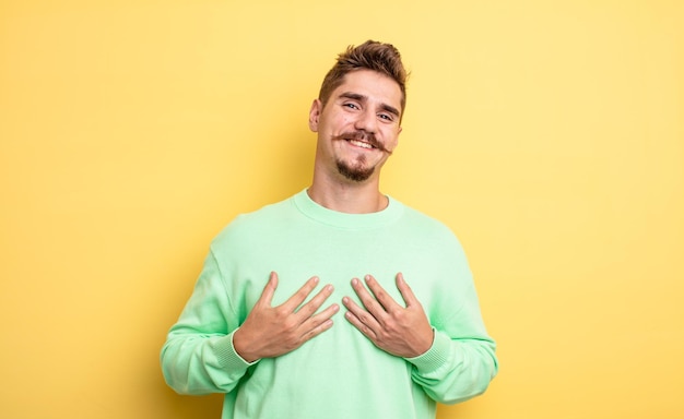 Hombre guapo joven que parece feliz, sorprendido, orgulloso y emocionado, apuntándose a sí mismo. extraño concepto de bigote