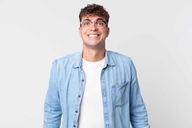 Hombre guapo joven que parece feliz y tonto con una sonrisa amplia, divertida y chiflada y los ojos bien abiertos