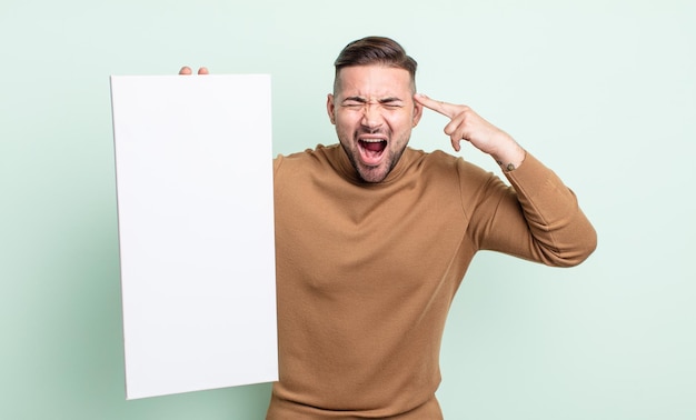 Hombre guapo joven que parece infeliz y estresado, gesto de suicidio haciendo signo de pistola. concepto de lienzo vacío