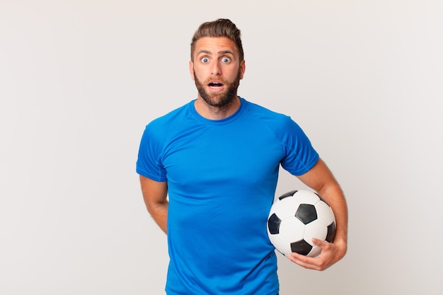 Hombre guapo joven que parece muy conmocionado o sorprendido. concepto de futbol