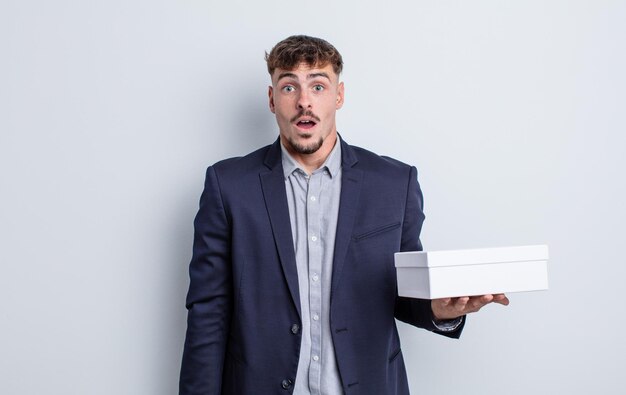 Hombre guapo joven que parece muy conmocionado o sorprendido. paquete de caja blanca