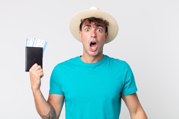 Hombre guapo joven que parece muy conmocionado o sorprendido. viajero sosteniendo su pasaporte