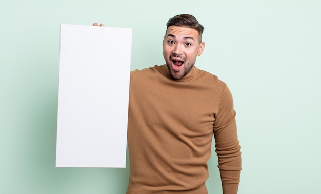 Hombre guapo joven que parece muy sorprendido o sorprendido. concepto de lienzo vacío