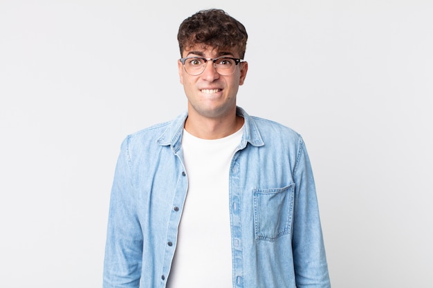 Foto hombre guapo joven que parece perplejo y confundido, mordiendo el labio con un gesto nervioso, sin saber la respuesta al problema