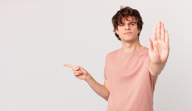 Hombre guapo joven que parece serio mostrando la palma abierta haciendo gesto de parada