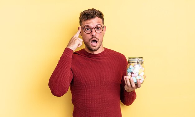 Hombre guapo joven que parece sorprendido al darse cuenta de una nueva idea de pensamiento o concepto concepto de caramelos de gelatina