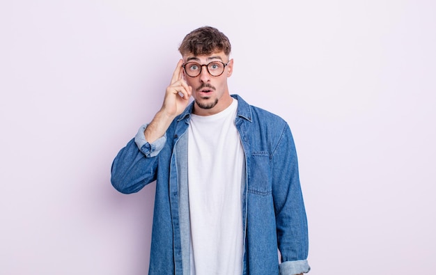 Hombre guapo joven que parece sorprendido, con la boca abierta, conmocionado, dándose cuenta de un nuevo pensamiento, idea o concepto