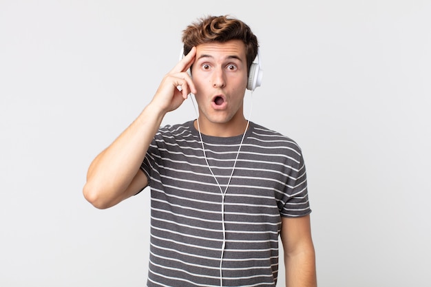 Hombre guapo joven que parece sorprendido, dándose cuenta de un nuevo pensamiento, idea o concepto. escuchando musica concepto