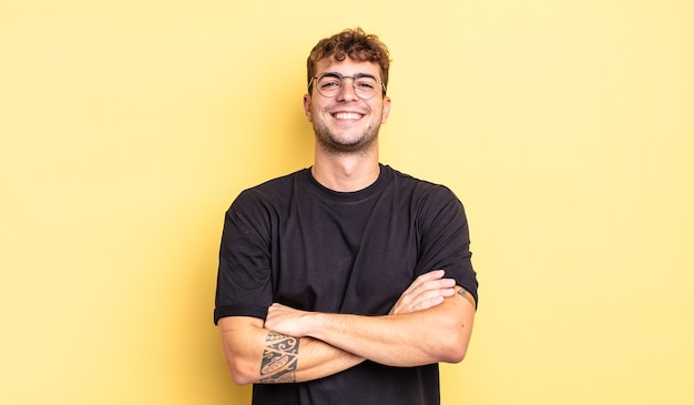 Hombre guapo joven que parece un triunfador feliz, orgulloso y satisfecho sonriendo con los brazos cruzados