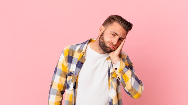 Hombre guapo joven que se siente aburrido, frustrado y con sueño después de un cansado