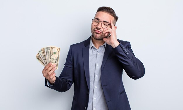 Hombre guapo joven que se siente aburrido, frustrado y con sueño después de un cansancio. concepto de billetes de dólar