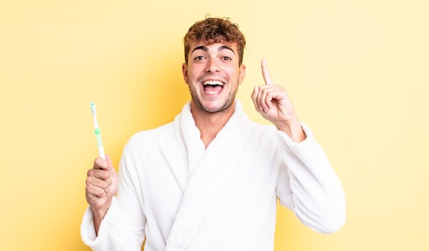 Hombre guapo joven que se siente como un genio feliz y emocionado después de darse cuenta de una idea. concepto de cepillo de dientes