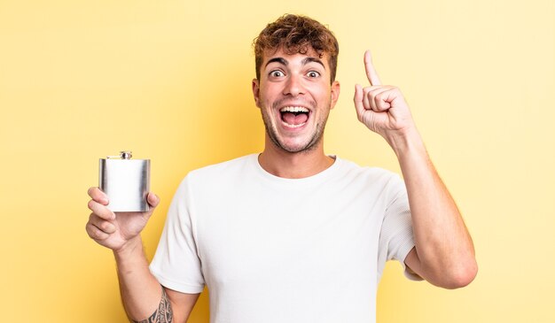 Hombre guapo joven que se siente como un genio feliz y emocionado después de darse cuenta de una idea. concepto de matraz de alcohol