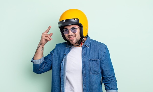 Hombre guapo joven que se siente confundido y desconcertado, mostrando que estás loco. concepto de casco de moto