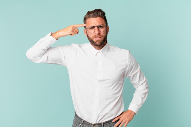 Hombre guapo joven que se siente confundido y desconcertado, mostrando que estás loco