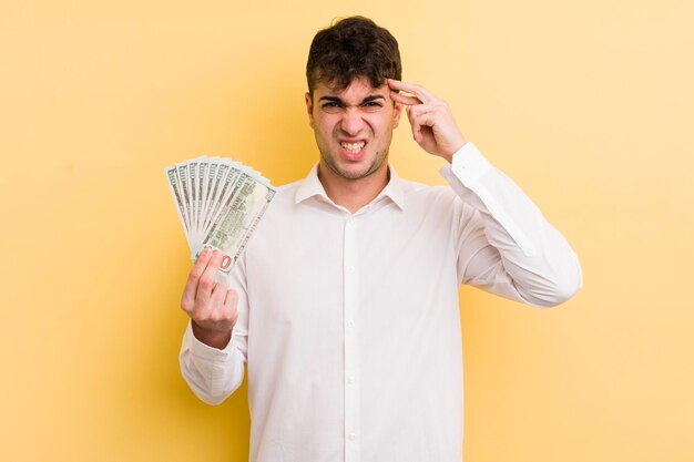 Hombre guapo joven que se siente confundido y perplejo mostrando que eres un concepto de dinero loco