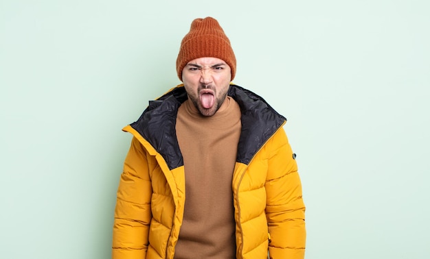 Hombre guapo joven que se siente disgustado e irritado y con la lengua fuera. concepto de clima frío