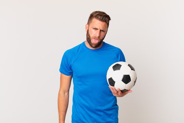 Hombre guapo joven que se siente disgustado e irritado y con la lengua fuera. concepto de futbol