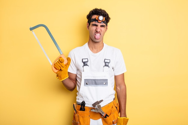 Hombre guapo joven que se siente disgustado e irritado y con la lengua fuera. concepto de reparación de manitas