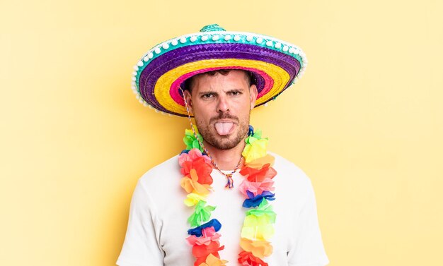 Hombre guapo joven que se siente disgustado e irritado y saca la lengua. concepto de fiesta mexicana