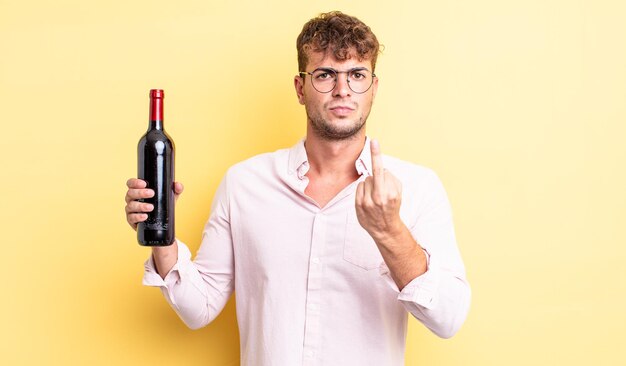 Hombre guapo joven que se siente enojado, molesto, rebelde y agresivo. concepto de botella de vino