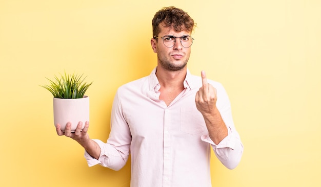 Hombre guapo joven que se siente enojado molesto rebelde y agresivo concepto de planta decorativa